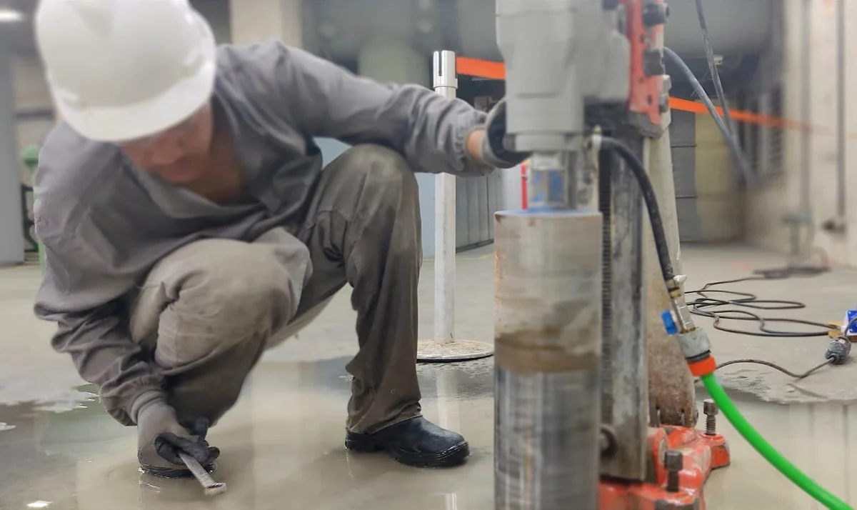 Alunos em treinamento prático, operando equipamento de perfuração em concreto